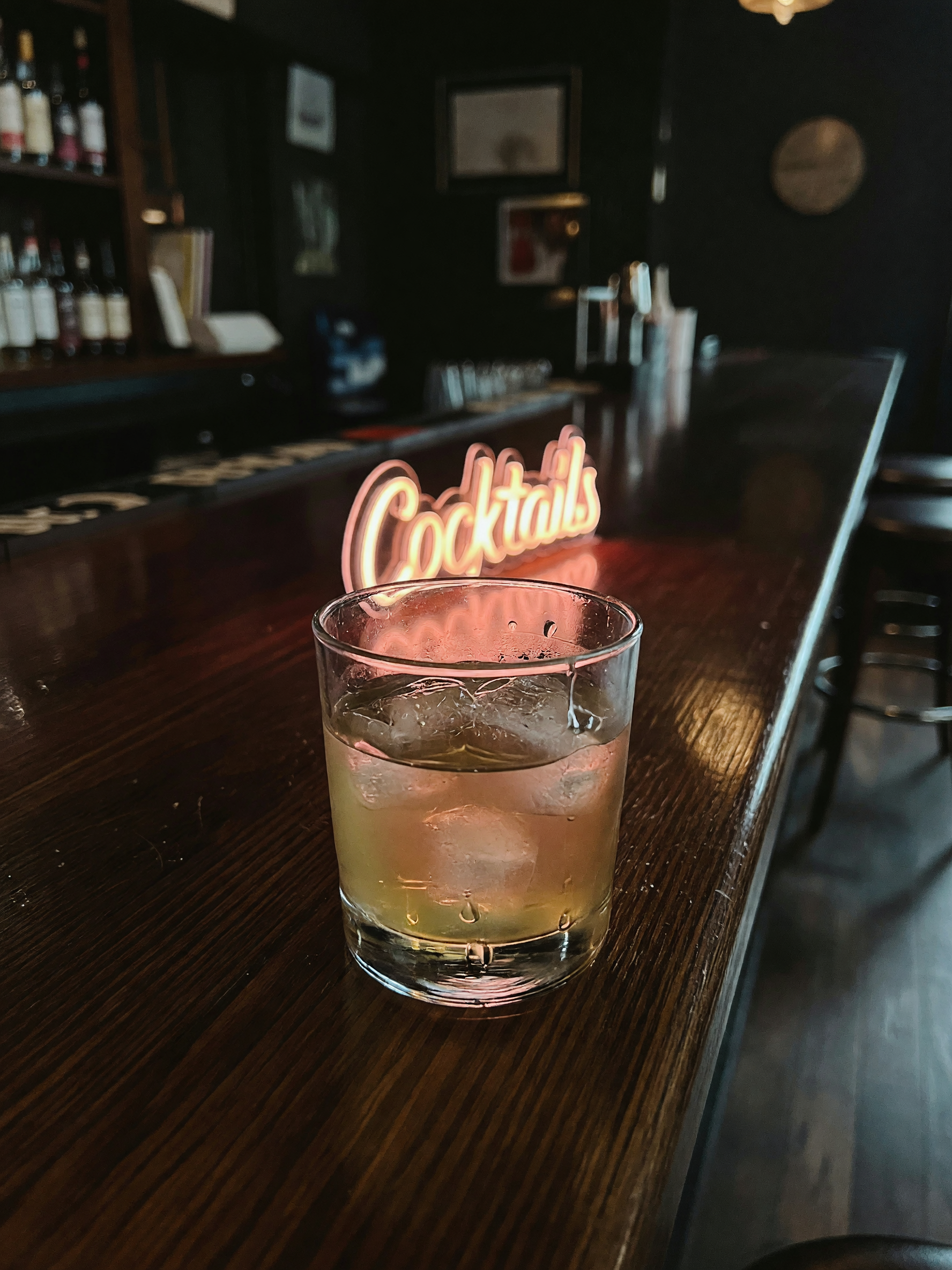 ice in the glass catching that low light. bartender doing that quiet wrist flick